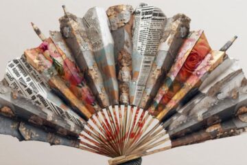 Artistic fan made from folded newspapers and magazine pages with painted textures, arranged like a sunburst.